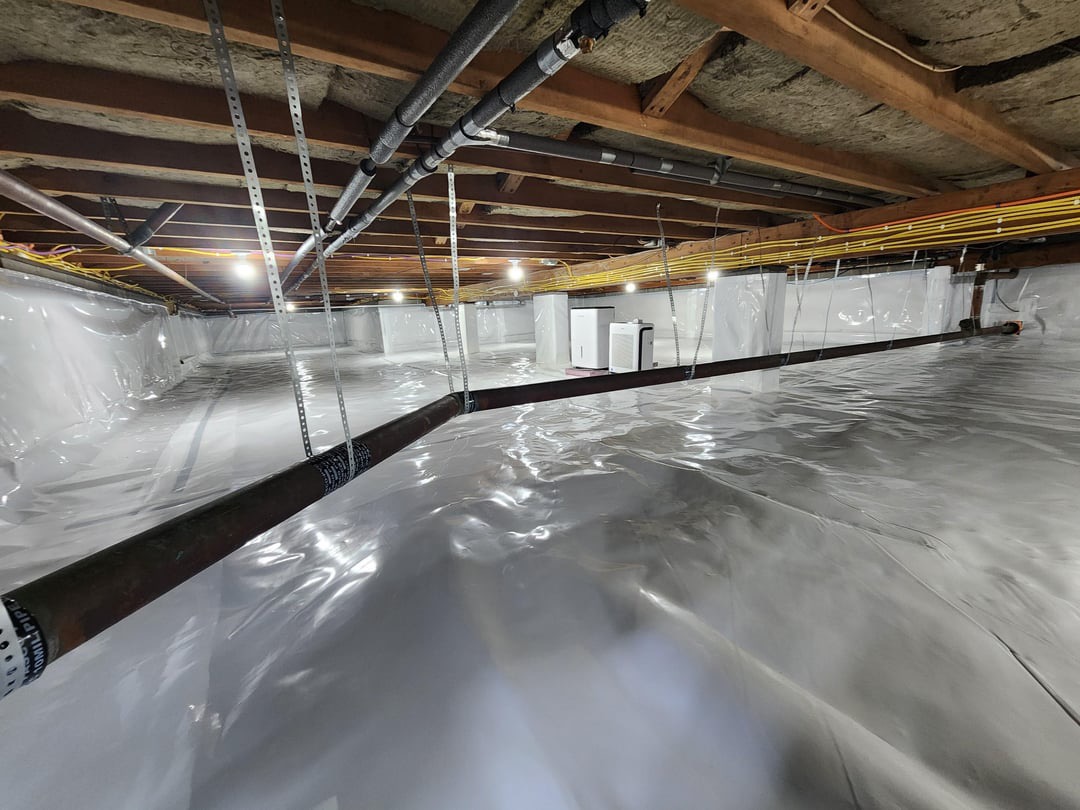 Encapsulated crawl space with a white vapor barrier, insulated floor joists and a dehumidifier